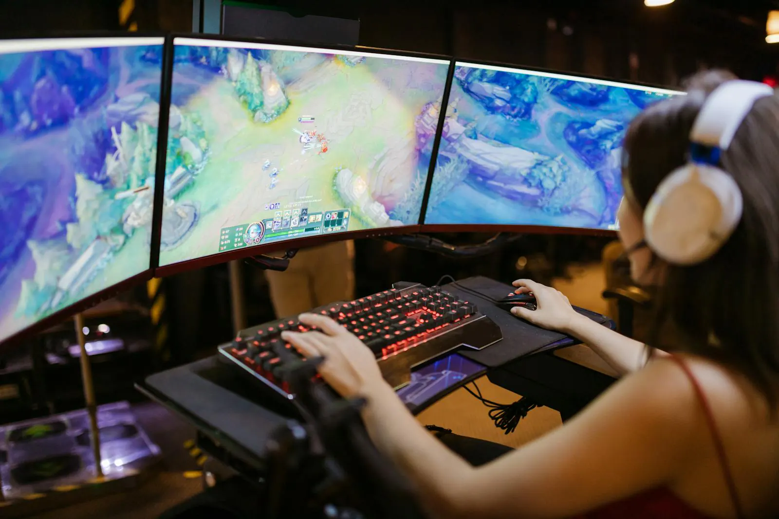 A player at a three monitor PC gaming setup wearing headphones